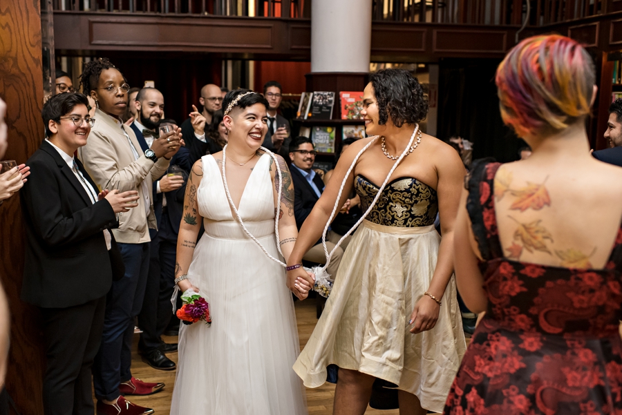 Two brides holding hands and smiling after getting married at the housing works bookstore in Manhattan.